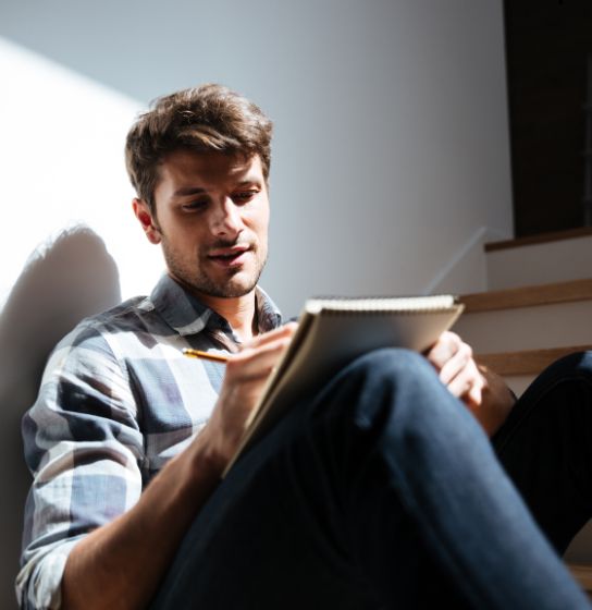 Man sitting in his home writing things into his journal